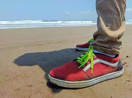 a pair of men's red shoes used on the beach sand photo