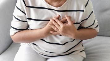 Closeup of Asian woman having heart attack. Woman touching breast and having chest pain. Healthcare And Medical concept. photo