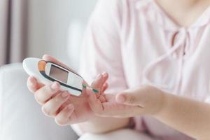 Asian woman checking blood sugar level by Digital Glucose meter, Healthcare and Medical, diabetes, glycemia concept photo