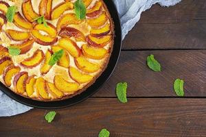 Delicious homemade peach pie on wooden background. Top view photo