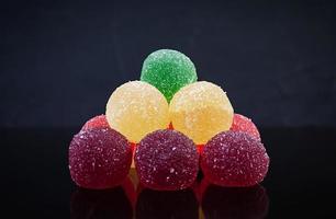 Colorful marmalade isolated on dark background. Delicious jujube balls. photo