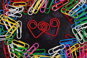 Colored paper clips isolated on dark background photo