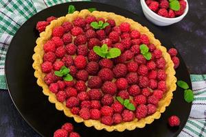 deliciosa tarta con natillas y frambuesa sobre fondo de madera foto