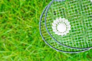 Shuttlecock and badminton rackets on a green lawn photo