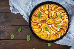 Delicious homemade peach pie on wooden background. Top view photo