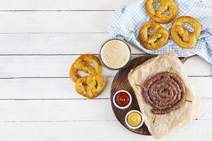 menú de comida para el oktoberfest. salchicha con salsa diferente, pretzel y vaso de cerveza oscura foto