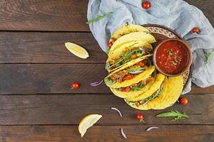 Mexican tacos with corn tortilla and meat on wooden background. Top view photo