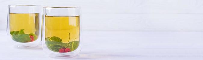 vaso de vidrio con té verde de bayas y menta. foto