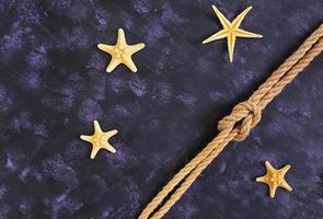 Rope and starfish on dark background. Top view photo