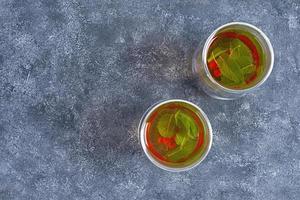 vaso de vidrio con té verde de bayas y menta. foto