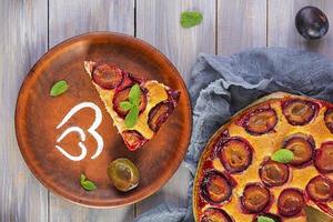 Delicious homemade plum pie on wooden background. Top view photo