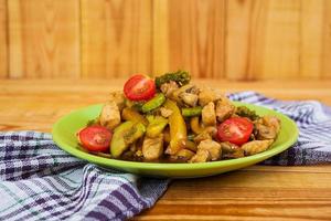 Stir fry chicken, zucchini and broccoli on wooden background photo