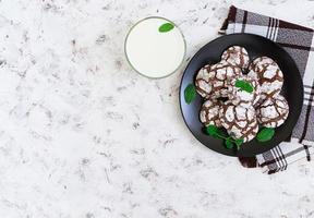 Chocolate cookies and a glass of milk on white background. Top view photo