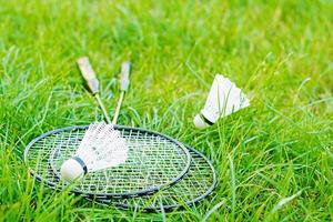 Shuttlecock and badminton rackets on a green lawn photo