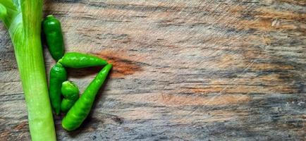 Vegetables of leek, garlic, and green chilli on the wooden cutting board. Vegetables ingredient background design. Suitable for advertising of food, drink, poster, backdrop, food company and industry. photo