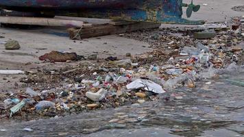 lixo marinho jogado por pessoas na praia envenena imagens de água do mar. video