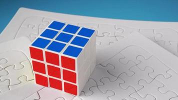 Rubik cube at the top of white jigsaw puzzle. video