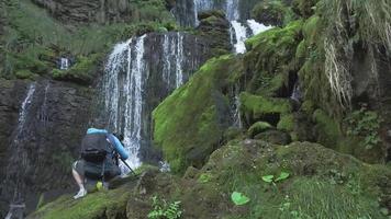 A nature photographer under a waterfall video