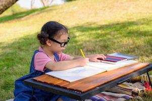 A little girl is sitting on the cloth and painted on the paper placed on a table photo