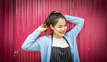 Girl holding her hair, smiling, seductive, charming, near the pink zinc wall. photo