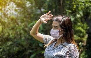 mujer con una máscara rosa y manos bloqueando el sol. foto