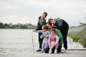 amor de padre papá con cuatro hijos al aire libre en el muelle. la familia numerosa deportiva pasa el tiempo libre al aire libre. foto