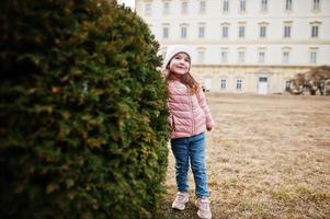 la chica usa una chaqueta rosa parada cerca de bush en el palacio de valtice, república checa. foto