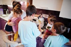 madre con hijos cocinando en la cocina, momentos felices de los niños. foto