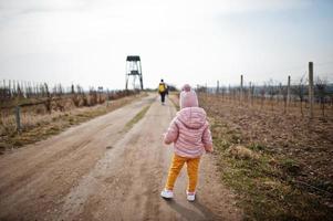 Little baby wear pink jacket walking on path of vineyard. photo
