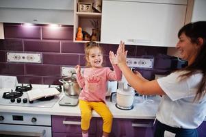 Mother with daughter cooking at kitchen, happy children's moments. photo