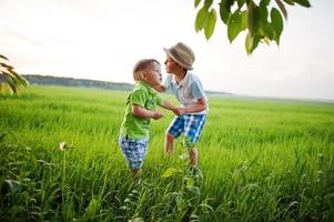 dos hermanos caminando tomados de la mano en el campo verde, amor de hermano. foto