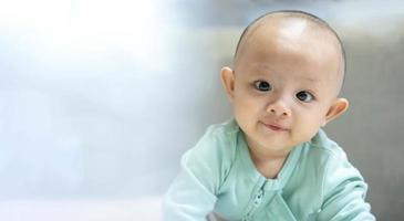 retrato de un adorable bebé recién nacido asiático mirando a la cámara y sonriendo cara feliz. pequeño e inocente niño recién nacido en el primer día de vida. concepto del día de la madre. foto