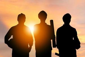 Success and Teamwork Concept, Silhouette of engineer and worker team with clipping path standing with sunset background photo