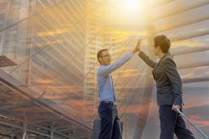 Success and Happiness Team concept, Business man Celebration putting their hands together in unity outside office sunset city double exposure background. photo