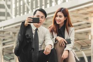 Joyful businessman and woman taking a selfie while sitting together at stairs photo