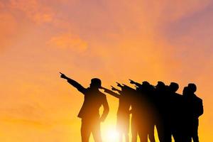 Silhouette of Business people success team with clipping path standing with pointing to the target sunset evening sky background, Success and Happiness Teamwork concepts photo