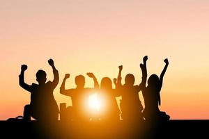 silueta de gente de negocios celebración éxito felicidad equipo al atardecer cielo de fondo foto