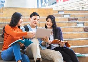 feliz grupo de estudiantes de secundaria asisten a un tutorial con un cuaderno en la escalera, conceptos educativos foto