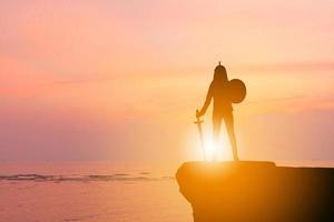 Silhouette of Businessman Knight sword and shield in sunset background, Fighting Business Warrior Concept. photo