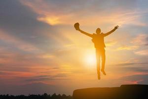 Silhouette of Business Engineer Man Celebration Success Happiness on a Stone Evening Sky Sunset at Beach Background, Sport and active life Concept. photo