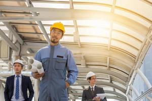 Business team engineer planing with white helmet and holding drawing paper in hand against city background planing and teamwork management concept photo