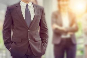 Close up of business man standing with hands in pocket over blurry background photo