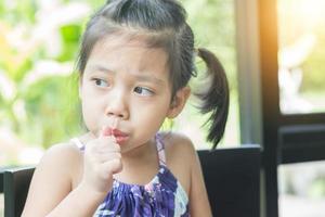 Little asian girl feeling happy while eating candy sticks photo