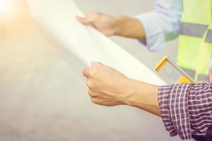 Close up of construction engineers with blueprint in hand working outdoors at construction site with copy space photo