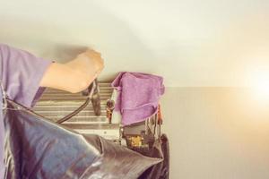 Technician repairing and cleaning dust filled air conditioning unit filters with water photo