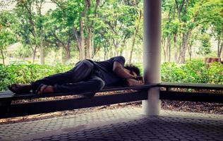 hombre sin hogar sentado en el suelo en el parque de las ciudades. foto