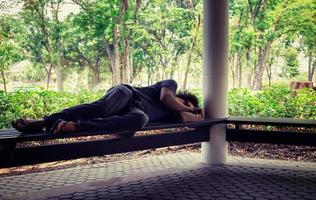 Homeless man sitting on the floor in the cities park. photo