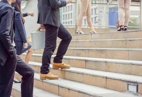 Businessman and Business woman walking up stairs with smartphone outside office photo