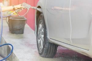 Car wash cleaning with soap and high pressure water washing, maintenance concept. photo