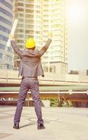 arquitecto ingeniero gerente celebración éxito felicidad con las manos arriba en el fondo de la ciudad foto